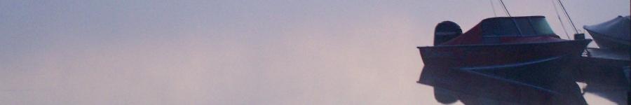 A pair of boats on a still lake in the dawn mist